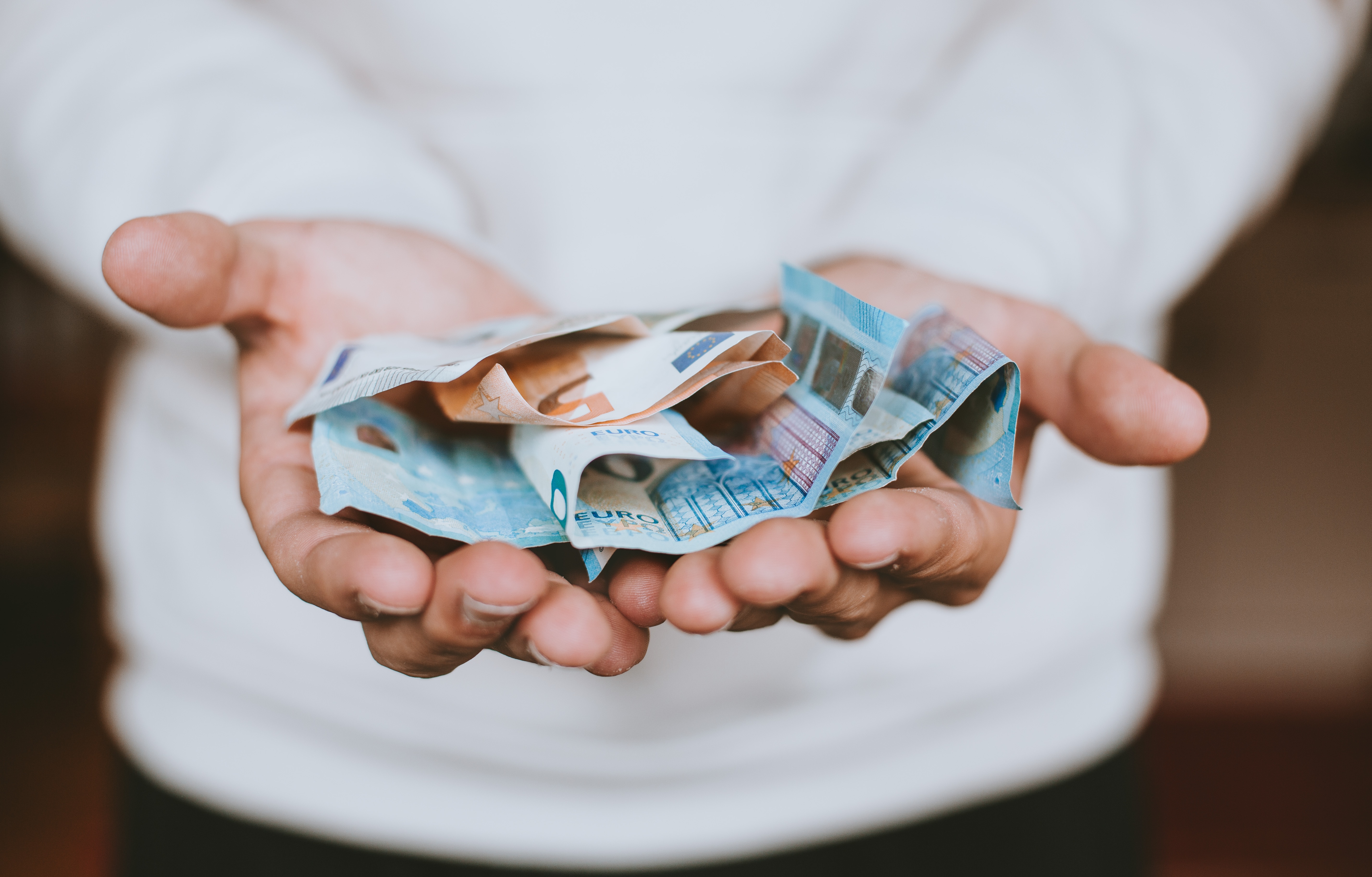 Person die Geld zum Spenden in der Hand hält.